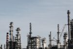 Skyline view of an industrial factory with tall chimneys against a clear sky.