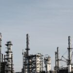 Skyline view of an industrial factory with tall chimneys against a clear sky.