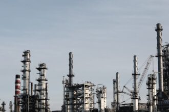 Skyline view of an industrial factory with tall chimneys against a clear sky.