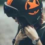 A woman adjusting a safety helmet on an outdoor road, emphasizing protective gear.