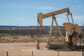 Industrial oil pumpjack in a desert setting under a clear blue sky, illustrating oil extraction technology.