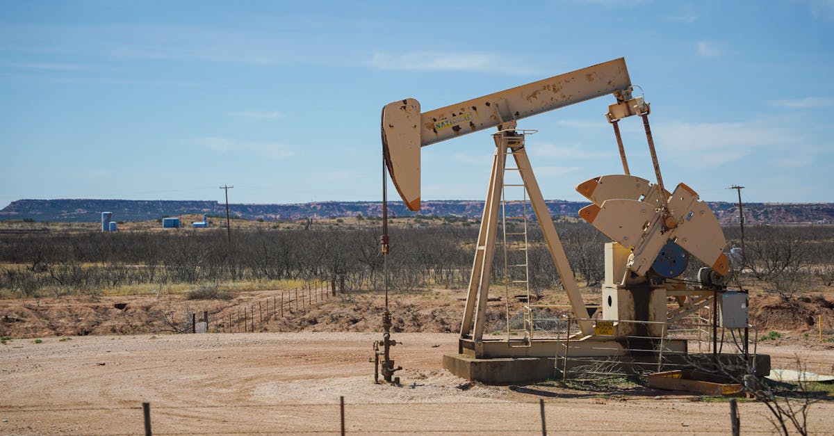 Industrial oil pumpjack in a desert setting under a clear blue sky, illustrating oil extraction technology.