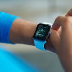 Person interacting with a smartwatch, showing a fitness application on the screen.