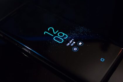 Close-up of a smartphone in the dark displaying digital clock and notifications.