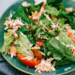 A vibrant green salad featuring mixed vegetables on a blue plate.
