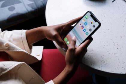 A person checks social media apps on a smartphone while sitting at a café table.