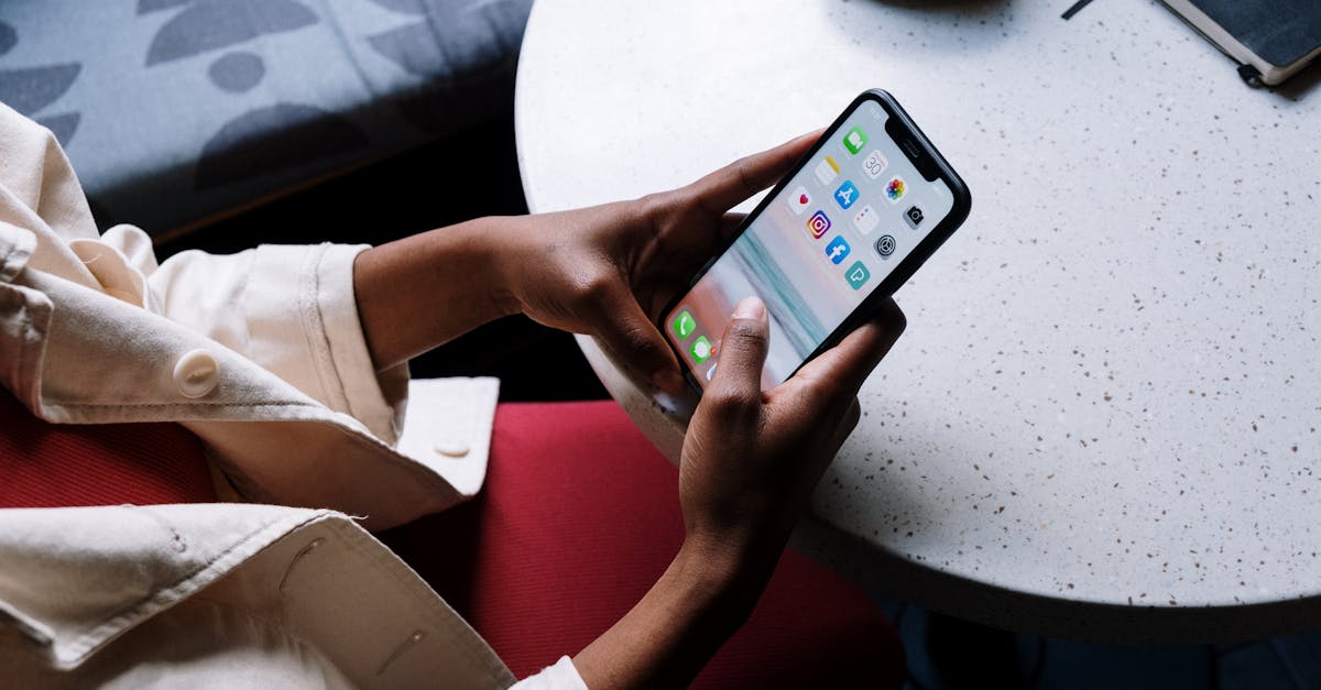 A person checks social media apps on a smartphone while sitting at a café table.