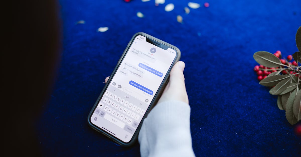 A person holding a smartphone displaying text messages on a blue surface with flowers.