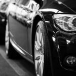 Close-up black and white image of a luxury car line-up focusing on vehicle headlights.