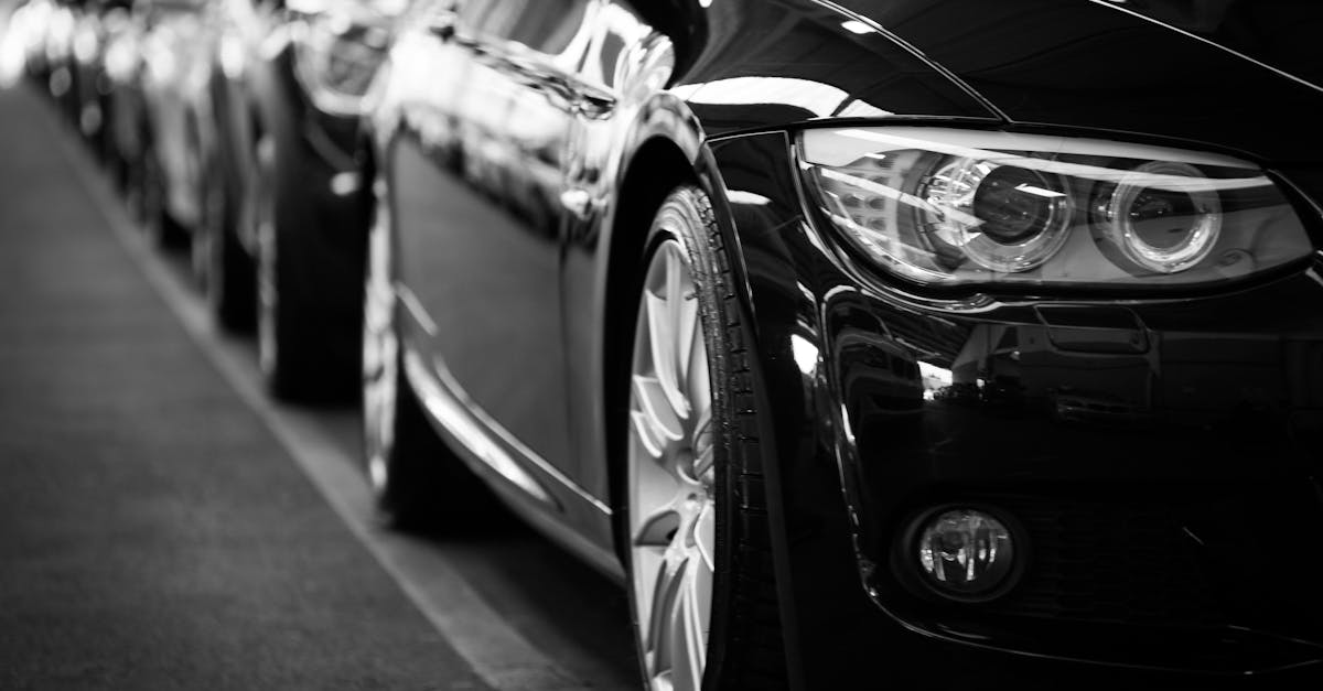 Close-up black and white image of a luxury car line-up focusing on vehicle headlights.