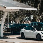 Electric car parked at a solar charging station outdoors, highlighting renewable energy and innovation.