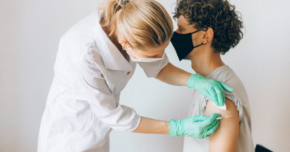 A healthcare worker gives a vaccine shot to a patient wearing a mask, highlighting medical safety and health precautions.
