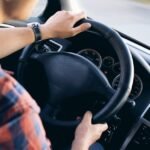 Close-up view of a man driving a modern car, showing dashboard and steering details.