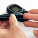 Close-up image of a person using a glucometer for diabetes management indoors.