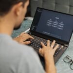 A man working on a laptop displaying ChatGPT's interface in an indoor setting.