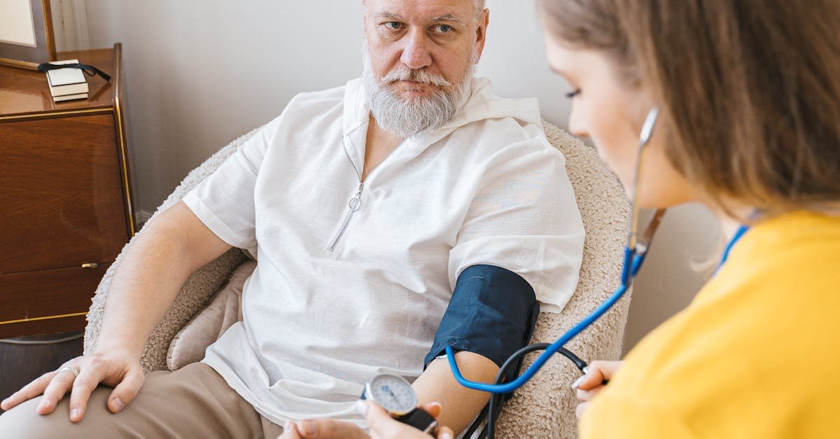 An elderly man having his blood pressure checked by a nurse during a routine health checkup indoors.