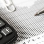 Close-up of a calculator and pen on a bar graph, representing finance and accounting.