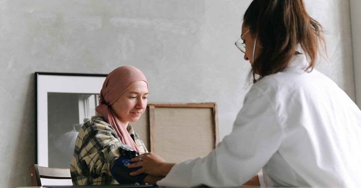 Doctor checks blood pressure of a patient wearing a headscarf indoors, focused on healthcare.
