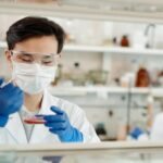 Researcher in a lab coat working on a scientific experiment with a petri dish and protective gear.