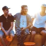 Three friends relax on a Tel Aviv rooftop, soaking up a vibrant sunset atmosphere.