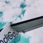 View of an airplane tail against a bright sky filled with clouds, showcasing travel themes.