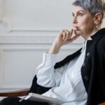 Elderly woman sitting thoughtfully in an elegant indoor setting, showcasing wisdom and contemplation.