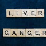 Scrabble tiles spell out 'Liver Cancer' on a dark blue background, symbolizing awareness.
