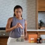 A woman uses essential oils and supplements in a contemporary kitchen for wellness.
