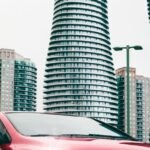 Red Honda car parked in front of distinctive twisted towers in Mississauga, Canada.