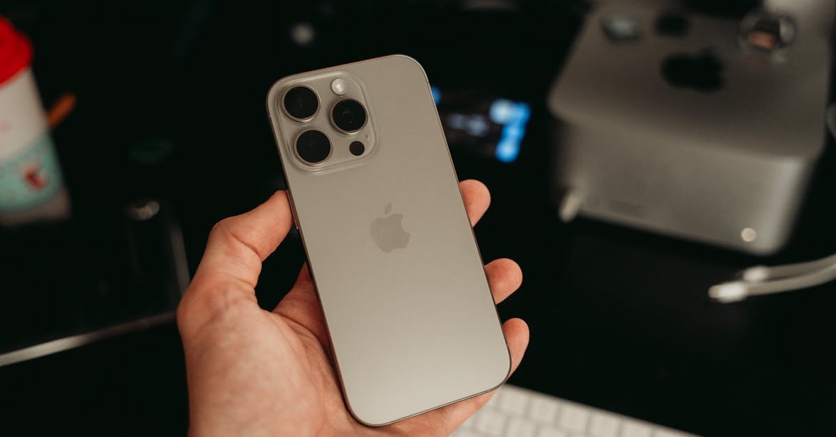 A hand holding a sleek smartphone in a tech-savvy office environment, showcasing its design.