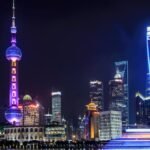 Stunning night view of Shanghai skyline with illuminated skyscrapers and the Oriental Pearl Tower reflecting in the water.