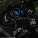 Detailed shot of a motorcycle dashboard, highlighting the instrument cluster and handlebar controls.
