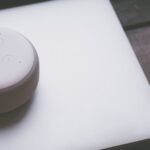 A smart speaker, laptop, and smartphone array representing modern technology lifestyle on a wooden surface.