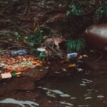 A riverbank littered with trash, highlighting environmental pollution and the need for recycling efforts.