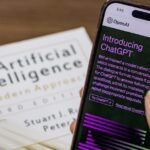 Close-up of a smartphone displaying ChatGPT app held over AI textbook.