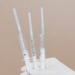 Close-up of gloved hand holding sterile syringes, symbolizing healthcare and vaccination.