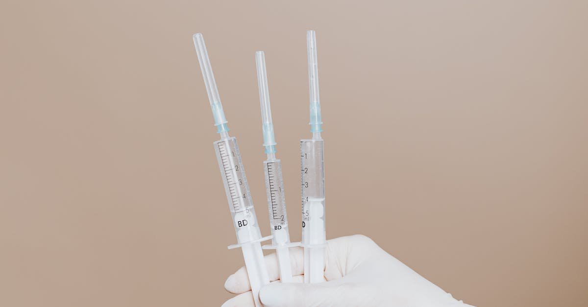 Close-up of gloved hand holding sterile syringes, symbolizing healthcare and vaccination.