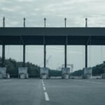 Empty toll gate on a deserted highway with overcast skies and surrounding greenery.