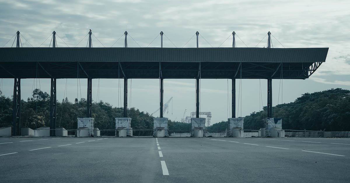 Empty toll gate on a deserted highway with overcast skies and surrounding greenery.