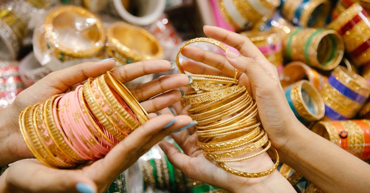 Vibrant close-up of hands displaying intricate golden bangles in a busy market setting.